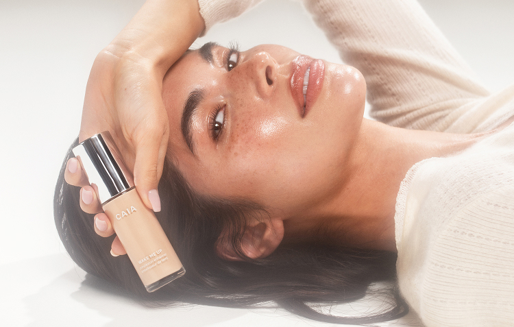 Woman wearing wake me up complexion enhancer and holding the bottle