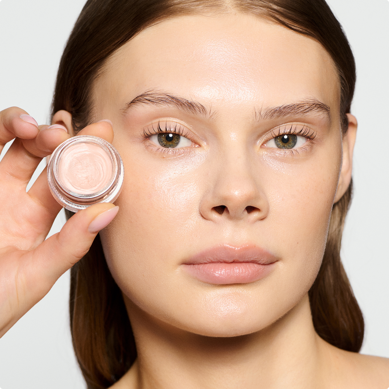 Woman wearing wake me up cream and holding the jar